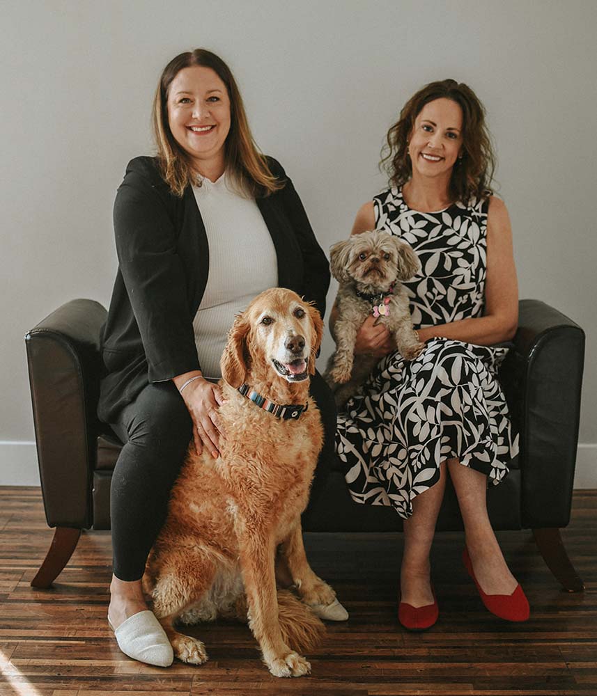 Photo of attorneys Christina Sambor and Carey Ziemann Goetz with their dogs